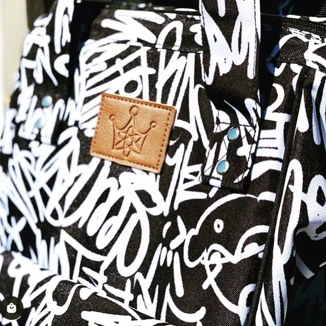 Macro of the debossed tan leather crown patch on the graffiti canvas.
