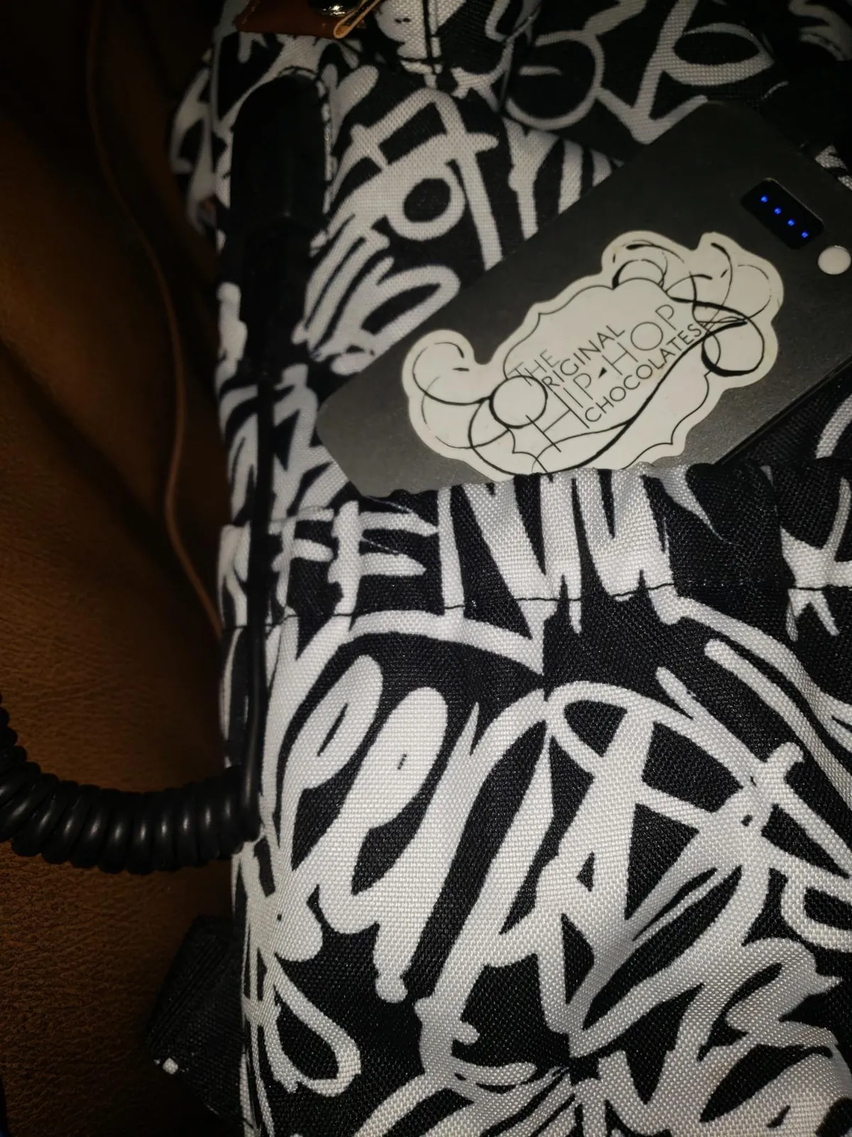 A power bank inserted into the bag's USB pass-through pocket.